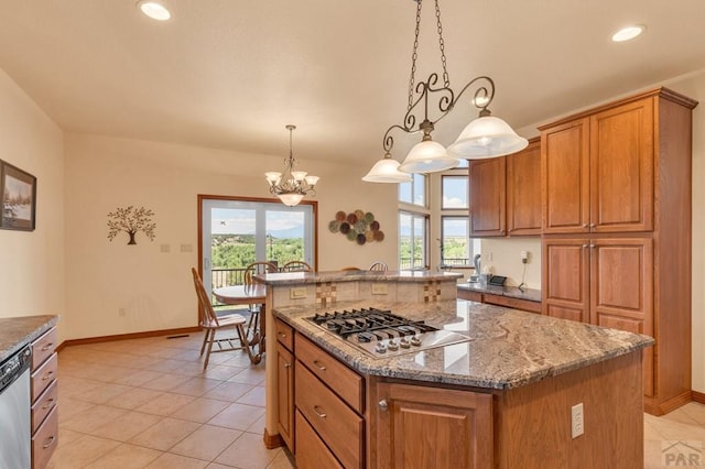 kitchen with appliances with stainless steel finishes, brown cabinetry, a kitchen island, and hanging light fixtures