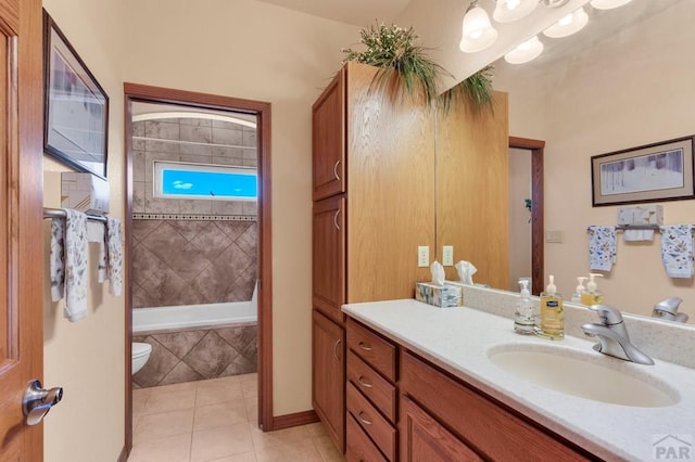 full bath with tile patterned flooring, vanity, toilet, and tiled tub