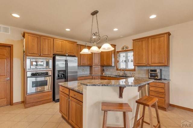 kitchen with stainless steel appliances, a center island, stone counters, and visible vents