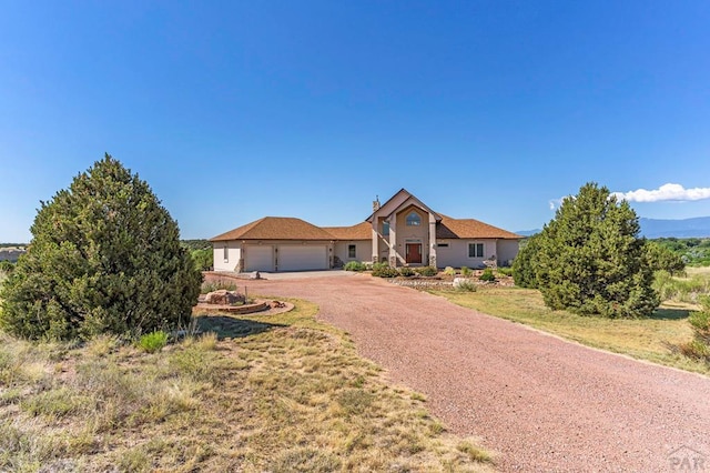 view of front facade with a garage, dirt driveway, and a front yard