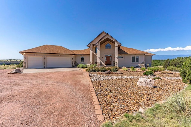 view of front of property featuring dirt driveway, stone siding, a garage, and stucco siding