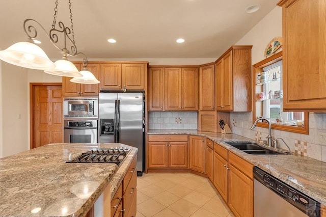 kitchen with brown cabinetry, light stone countertops, stainless steel appliances, pendant lighting, and a sink