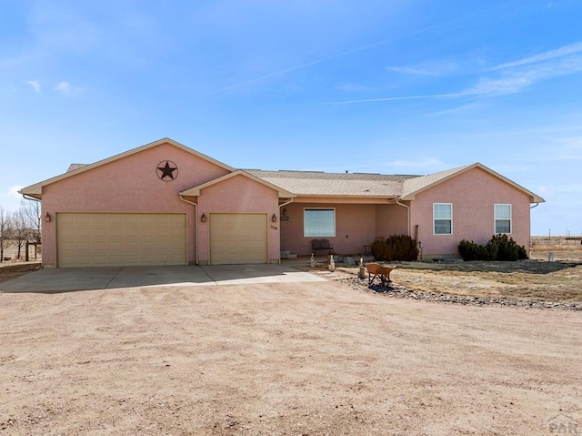 ranch-style house with driveway, a garage, and stucco siding