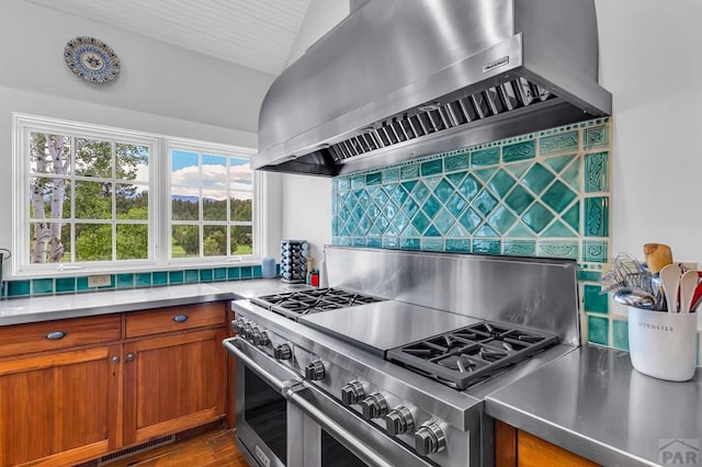 6430 Signal Mountain Rd, Beulah, CO 81023 - kitchen with wall chimney range hood, double oven range, lofted ceiling, brown cabinetry, and light countertops