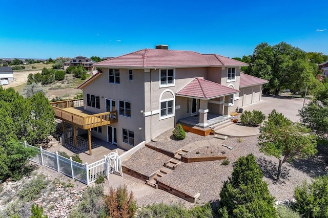 back of property featuring stucco siding, an attached garage, fence private yard, driveway, and a tiled roof