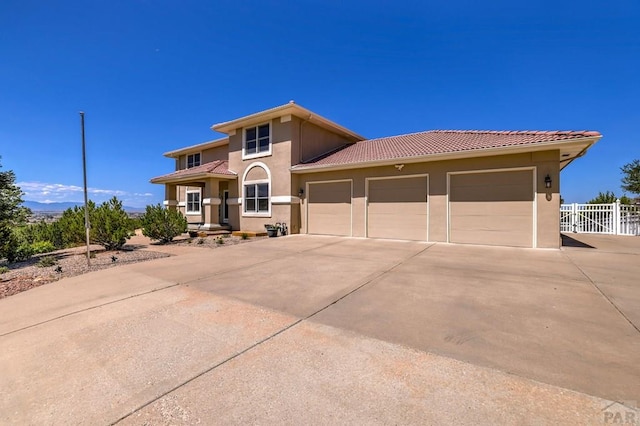 view of front of house with a garage, fence, concrete driveway, a tiled roof, and stucco siding