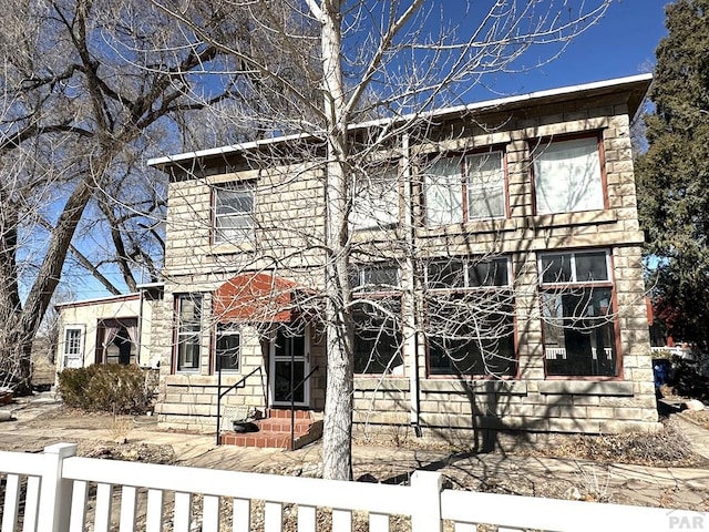 view of front of house with a fenced front yard, stone siding, and entry steps