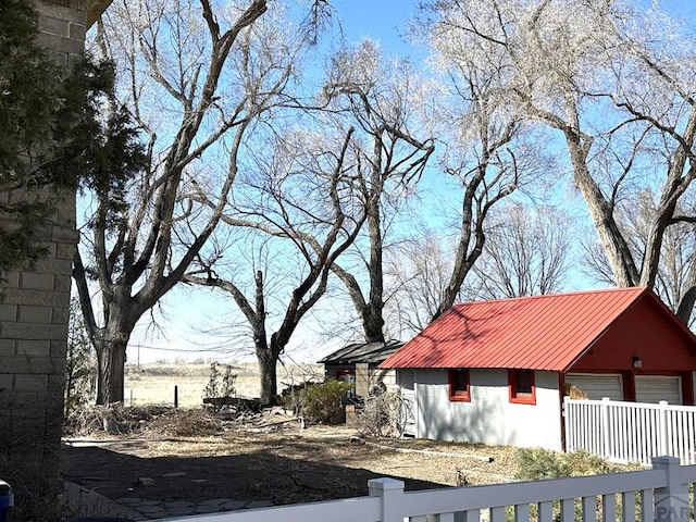 exterior space featuring a garage, a fenced front yard, and metal roof