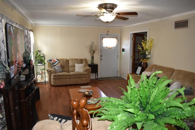 living area featuring a ceiling fan, visible vents, ornamental molding, and dark wood-type flooring