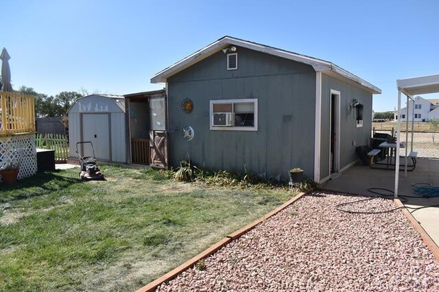 back of property featuring a storage shed, a lawn, fence, an outdoor structure, and a patio area