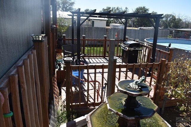 wooden terrace with a fenced backyard, a fenced in pool, and a grill