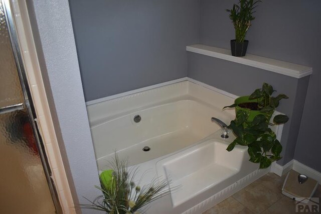 full bath with a garden tub and tile patterned floors