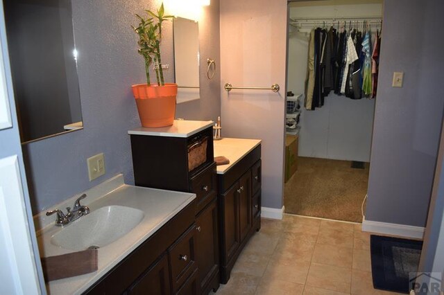 bathroom with vanity, tile patterned flooring, a walk in closet, and baseboards