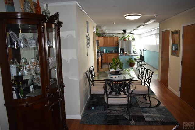 dining space with crown molding, baseboards, and wood finished floors