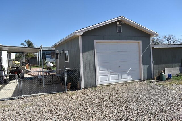 detached garage featuring gravel driveway and fence