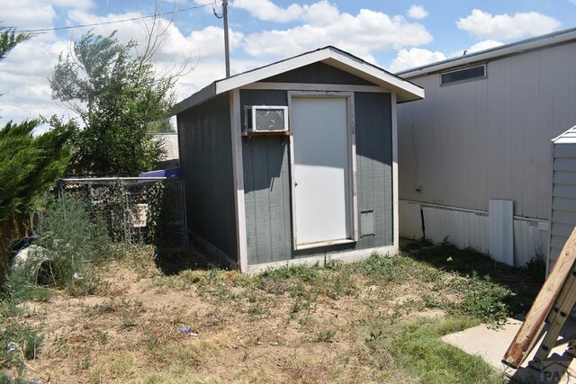 view of shed with a wall unit AC and fence