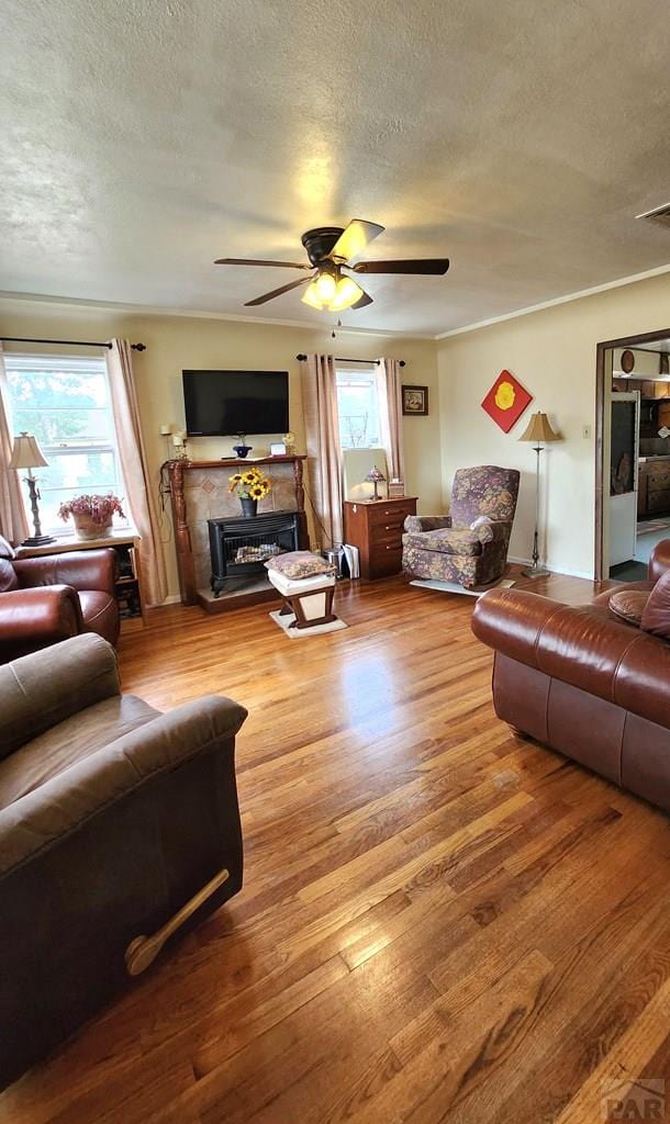 2631 Cedar St, Pueblo, CO 81004 - living area featuring a ceiling fan, a textured ceiling, wood finished floors, and a fireplace with raised hearth