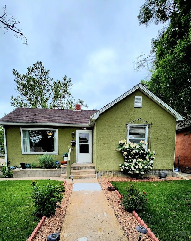 2631 Cedar St, Pueblo, CO 81004 - view of front of home featuring stucco siding, a front lawn, entry steps, and a chimney