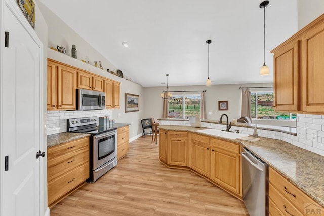 1284 N Challenger Dr, Pueblo West, CO 81007 - kitchen with stainless steel appliances, a peninsula, lofted ceiling, a sink, and decorative backsplash