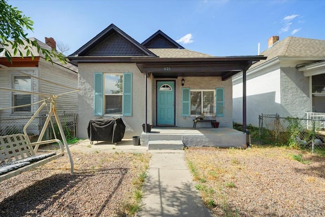 view of front of property with covered porch, fence, and stucco siding