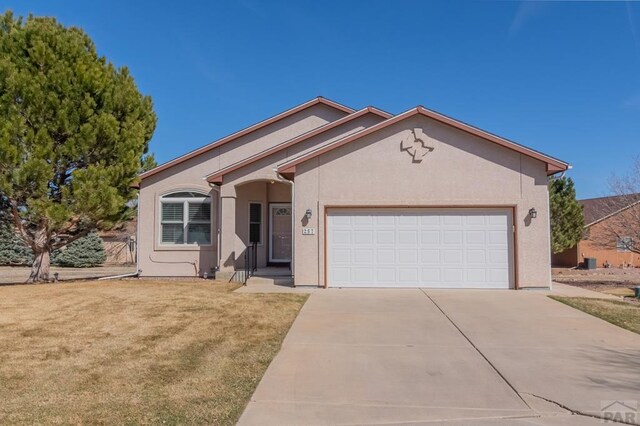 single story home featuring driveway, a front lawn, an attached garage, and stucco siding