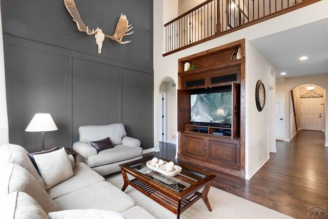 4288 Cedarweed Blvd, Pueblo, CO 81001 - living area with arched walkways, dark wood finished floors, a decorative wall, a towering ceiling, and recessed lighting