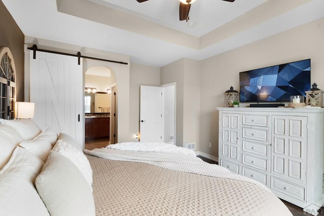 4288 Cedarweed Blvd, Pueblo, CO 81001 - bedroom featuring arched walkways, dark wood-style floors, ensuite bathroom, ceiling fan, and a tray ceiling