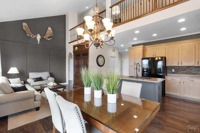 4288 Cedarweed Blvd, Pueblo, CO 81001 - dining room featuring a chandelier, dark wood-type flooring, arched walkways, a decorative wall, and a towering ceiling
