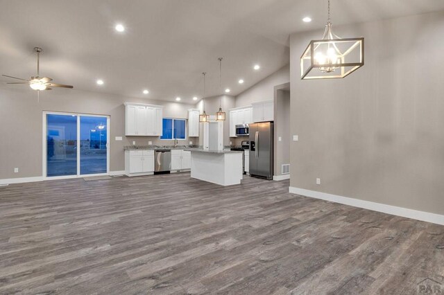 kitchen with white cabinets, open floor plan, appliances with stainless steel finishes, a center island, and decorative light fixtures