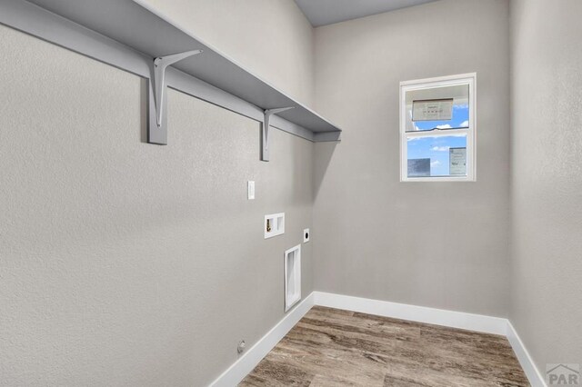 clothes washing area with laundry area, baseboards, gas dryer hookup, wood finished floors, and washer hookup