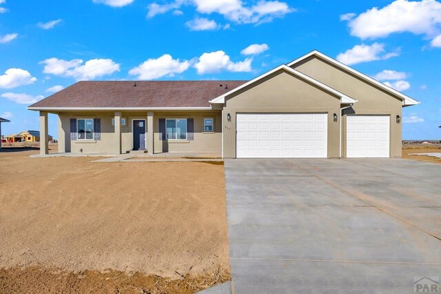 ranch-style house with driveway, an attached garage, and stucco siding