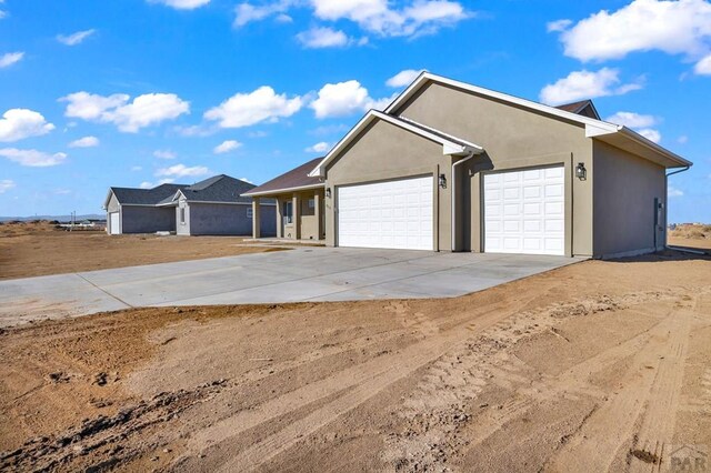 view of front of house with a garage, concrete driveway, and stucco siding