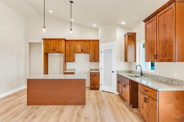 kitchen featuring brown cabinetry, pendant lighting, a sink, and a center island