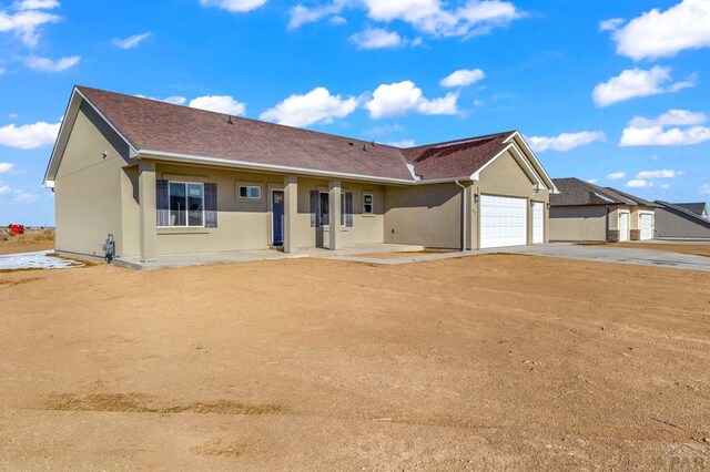 single story home with an attached garage, driveway, roof with shingles, and stucco siding