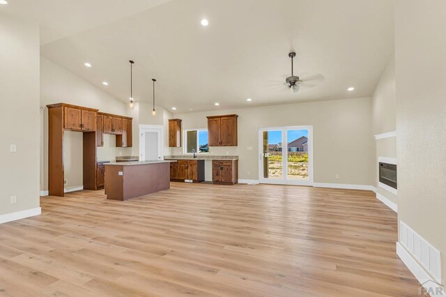 kitchen featuring brown cabinetry, a kitchen island, visible vents, and open floor plan