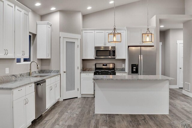 kitchen with pendant lighting, stainless steel appliances, a sink, and a center island