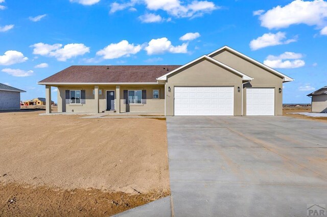 ranch-style home with covered porch, driveway, an attached garage, and stucco siding