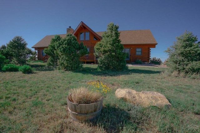 log home featuring a chimney, log siding, a front lawn, and a wooden deck