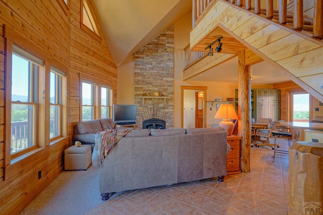 living area featuring wood walls, plenty of natural light, a fireplace, and light tile patterned floors