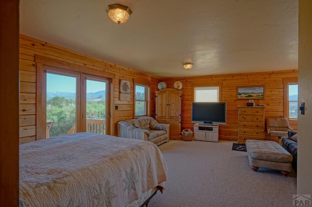 carpeted bedroom featuring access to exterior and wood walls