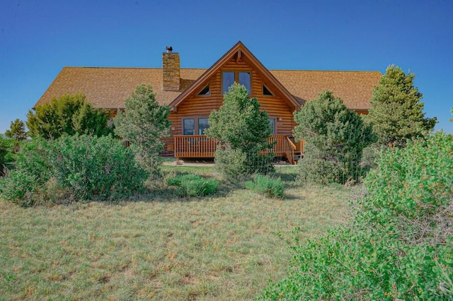 rear view of property featuring a shingled roof, a chimney, and a deck