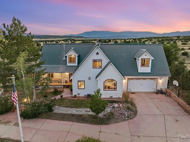 modern farmhouse style home with metal roof, a mountain view, driveway, and stucco siding