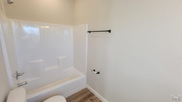 full bathroom featuring shower / tub combination, toilet, wood finished floors, and baseboards