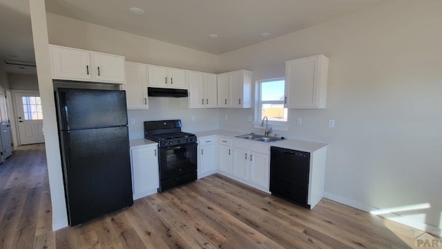 kitchen with black appliances, a sink, under cabinet range hood, white cabinets, and light countertops