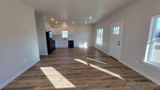 unfurnished living room featuring visible vents, baseboards, recessed lighting, wood finished floors, and a sink