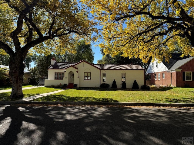 view of front of home with a chimney, stucco siding, and a front lawn