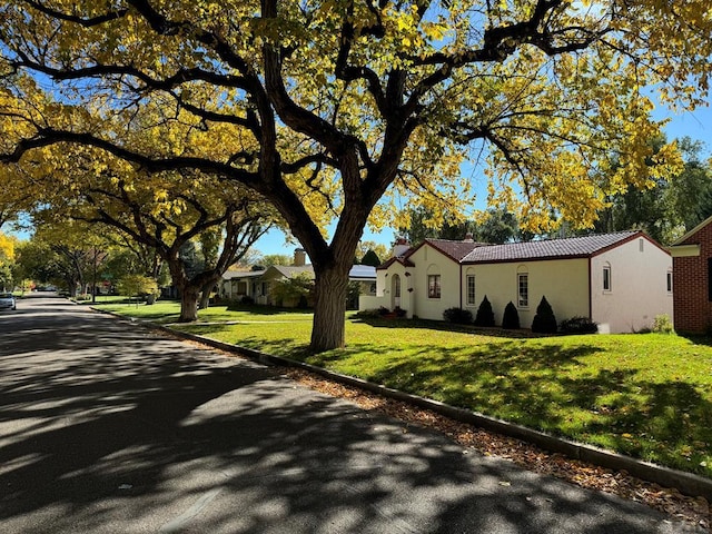 view of front of home with stucco siding, a tiled roof, and a front lawn