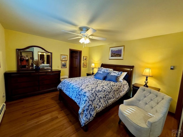 bedroom featuring wood finished floors, a baseboard heating unit, and ceiling fan