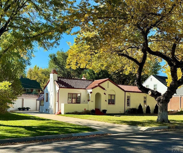 mediterranean / spanish home with concrete driveway, a front yard, stucco siding, and a tiled roof