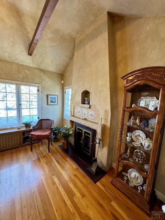 living area featuring light wood-style flooring, high vaulted ceiling, and a fireplace